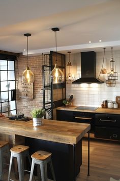 a kitchen with wooden counter tops and stools next to an island in front of a brick wall