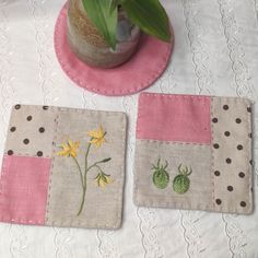 two coasters with flowers on them sitting on a table next to a potted plant