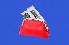 a red purse with money sticking out of it's side on a blue background