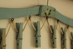 several pieces of wood hanging from hooks on a wall with rope attached to them and painted blue