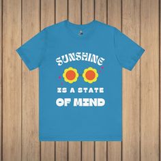 Brighten up your wardrobe with the 'Sunshine State of Mind' Unisex Tee, exuding hippie vibes and positive energy. Featuring a playful graphic of retro flower sunglasses, this tee spreads good vibes and reminds you that sunshine is a state of mind. Crafted from 100% Airlume combed and ring-spun cotton, this tee offers a lightweight and breathable fabric perfect for both active and leisure wear. The classic crew neckline and ribbed knit collars provide a timeless look, while the tapered shoulders Retro Summer T-shirt With Slogan, Fun Slogan T-shirt For Spring, Funny Graphic Print T-shirt For Spring, Retro Pre-shrunk T-shirt For Summer, Hippie Tops With Funny Print For Spring, Funny Slogan T-shirt For Summer, Retro Text Print T-shirt For Summer, Hippie Top With Funny Print For Spring, Spring Hippie Top With Funny Print