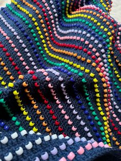 a multicolored crocheted blanket is laying on the floor