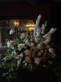 white flowers and greenery in front of a window