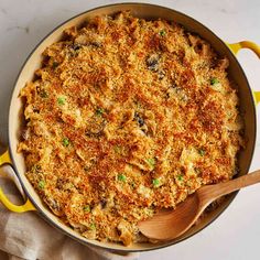 a casserole dish in a yellow pan with a wooden spoon on the side