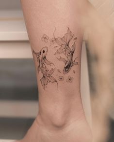 a woman's foot with two goldfish tattoos on it