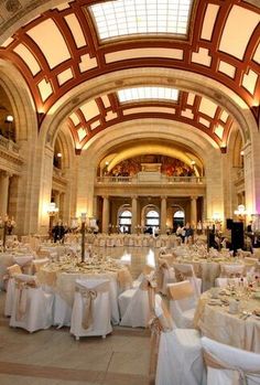 the inside of a building with tables and chairs set up for a formal function in white linens