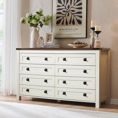 a white dresser with drawers in front of a window and vases on top of it