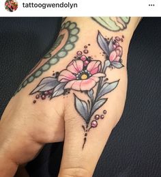 a woman's hand with a flower tattoo on it