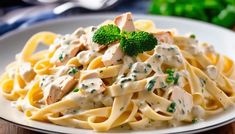 a white plate topped with pasta covered in sauce and broccoli florets