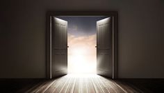 an open door leading to the sky with light coming in from behind it on a wooden floor