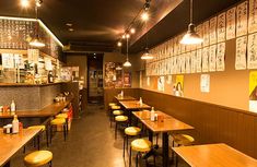 an empty restaurant with wooden tables and yellow stools