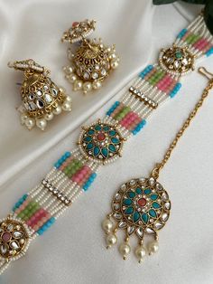 pearl  pastel kundan choker set with tikka set x jhumki lightweight earrings  Style tip- ----------- Pair it with any beautiful traditional outfits  and flaunt with Unique style of collection from us. Perfect match for Festival and Traditional wear.  Take Care Tips-  ---------------- Kee away from perfume, Hair spray and. Moisture.  Store in dry place , Ziplock bag or Airtight box.    Clean with dry cloth.  Jewellery is the last thing you should wear and first thing you should remove.  --------- Multicolor Tilla Choker, Multicolor Festival Choker Jewelry, Multicolor Choker Jewelry For Diwali, Round Mirror Work Jewelry For Festivals, Round Festival Jewelry With Mirror Work, Multicolor Kundan Choker Necklace, Multicolor Mirror Work Jewelry Gift, Multicolor Meenakari Choker Jewelry, Adjustable Meenakari Jewelry For Diwali