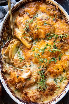 a casserole dish with chicken, potatoes and gravy topped with fresh herbs