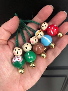 a hand holding several different colored beads in it's palm with bells attached to them