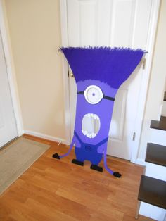 a purple monster costume sitting on top of a hard wood floor next to a white door