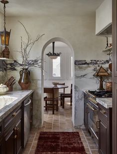 a kitchen with marble counter tops and wooden cabinets, along with a red rug on the floor