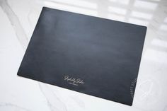 a black folder with writing on it sitting on a marble counter top next to a window