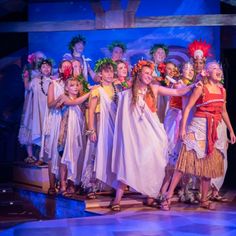 a group of children standing on top of a stage wearing costumes and headdress