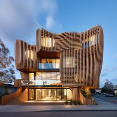 an unusual building with wooden slats on the outside and windows in the inside is lit up at night