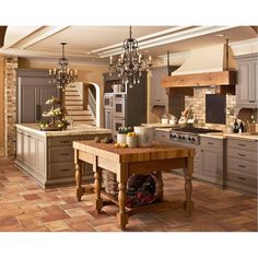 a large kitchen with an island in the middle and chandelier hanging from the ceiling