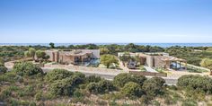 an aerial view of a house surrounded by trees and shrubs with the ocean in the background