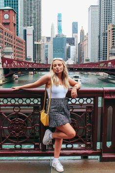 a woman leaning on a railing in front of the city skyline with her hand on her hip