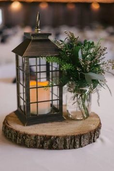 a candle and some greenery in a glass jar on a wood slice at a wedding reception