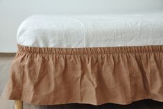 a bed with a white and brown bedspread on top of wooden flooring