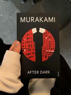 a person holding up a book with the title'after dark'in front of them