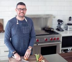 a man standing in front of a cutting board with vegetables on it