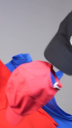 two hats on top of each other in front of a gray background with red and blue material