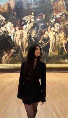 a woman standing in front of a large painting