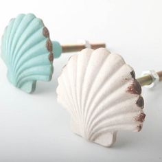 two seashells are sitting next to each other on a white surface, one is green and the other is blue