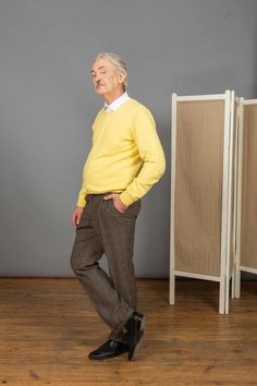 an older man in a yellow sweater and brown pants