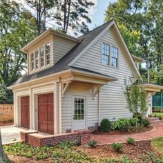 a small white house with a red door and brown shutters on the front porch