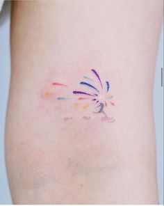 a small tattoo on the side of a woman's leg that has colorful fireworks coming out of it