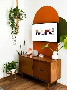 a living room with some plants on the table and a large painting hanging above it