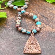 Wear this gorgeous handmade necklace to your next beach party or BBQ, and your friends will think you just returned from Thailand.  Indeed, the copper Buddha amulet was made by hand by Thai artisans, and adorns our Crazy Lace Agate 108 bead gemstone mala necklace.  Crazy Lace Agate gemstones have gorgeous sky and ocean blue turquoise colors, mixed with tans and browns. A perfect addition or souvenir, you choose, to your boho or spiritual jewelry collection. -Gemstone mala necklace composed of 108 6mm round Crazy Lace Agate gemstone beads with 1 handcrafted Ethiopian brass metal counter bead, and 2 copper beads up-cycled from an antique Thai prayer necklace. -Approximately 25 inches in length. -Pendant 1 inch long including ring. -Clasp-less, slips overhead, hand strung with silk or nylon t Spiritual Copper Beaded Necklaces As Gift, Bronze Spiritual Hand Wrapped Necklaces, Spiritual Bronze Hand Wrapped Necklaces, Spiritual Beaded Copper Necklaces, Spiritual Copper Necklace For Meditation, Bohemian Copper Beaded Necklaces With Round Beads, Sky And Ocean, Buddha Pendant Necklace, 108 Mala Beads