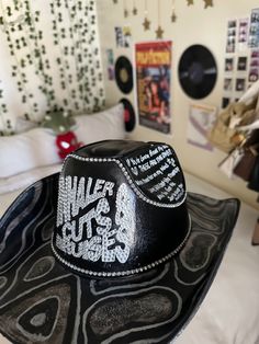 a black hat sitting on top of a bed in a room filled with posters and pictures