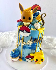 a pokemon themed birthday cake with pikachu and cupcakes