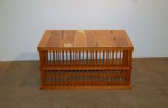 a wooden birdcage sitting on top of a floor next to a white wall