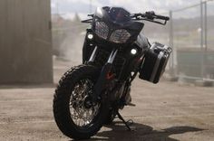 a black motorcycle parked on top of a parking lot next to a tall metal structure