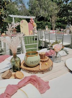 the table is set with flowers, plates and vases for guests to sit at