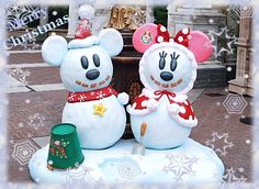 mickey and minnie mouse christmas decorations in front of a fountain with snowflakes on it