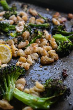 broccoli and chickpeas are being cooked in a pan with lemon wedges