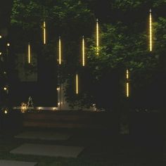 some lights that are hanging from the side of a building in front of a tree