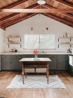 a kitchen with wood floors and white walls, wooden beams on the ceiling is an island