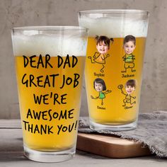 two glasses filled with beer sitting on top of a wooden table next to each other