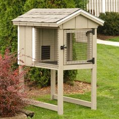 a chicken coop in the middle of a yard with grass and bushes around it,