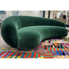 a large green couch sitting on top of a colorful rug